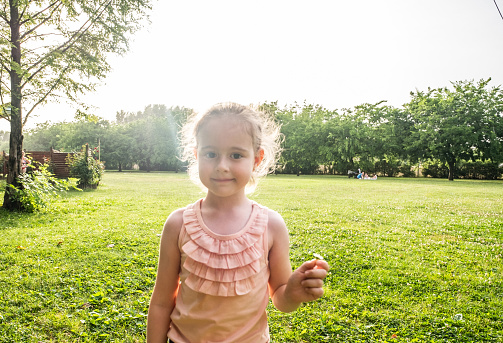 A small, cute girl is holding a flower in her hand.