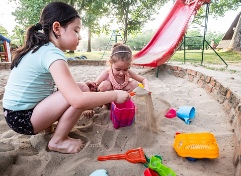 Little cute girls are playing together with the sand