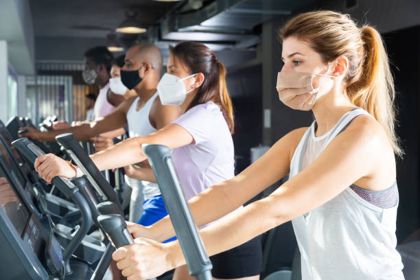 istock Active people in protective masks having running elliptical trainer class in club 1466818192
