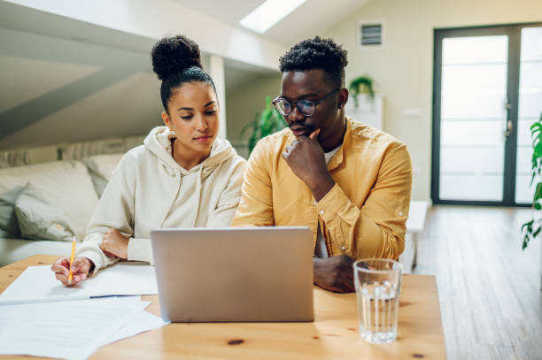 istock Diverse couple using laptop while sitting at the table at home 1466820689