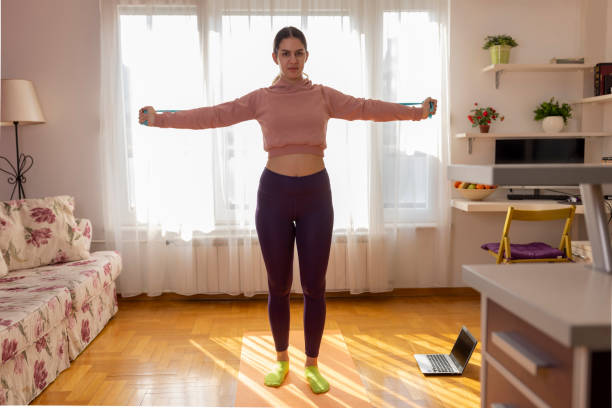 istock A beautiful teen girl training while watching online workout tutorials on laptop at home 1466824068