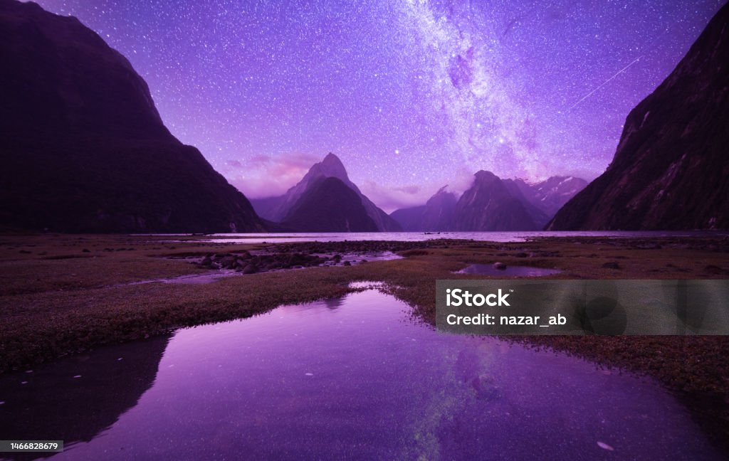Milky ways at Milford Sounds. Milford Sounds iconic view with reflection over water and night full of stars and Mitre Peak in Fiordland National Park, South Island, New Zealand. New Zealand Stock Photo