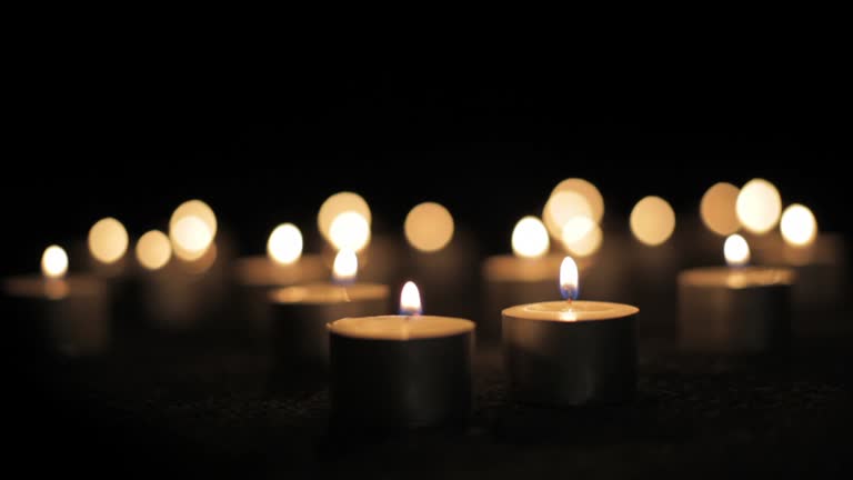 Multiple short decorative candles burning in darkness