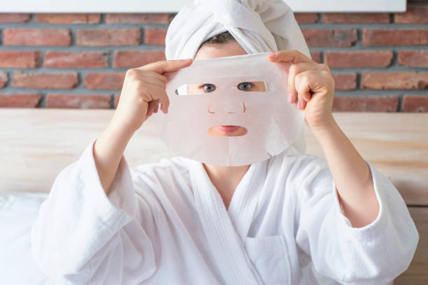 Portrait of young woman who is put on face of sheet moisturizing mask. stock photo