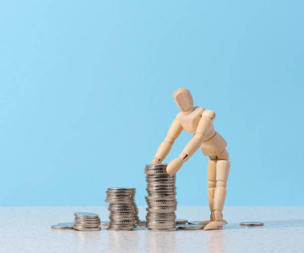 istock Wooden mannequin and a stack of coins on a blue background 1466833102