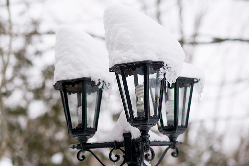 Closeup of a city lamp post layered with a large amount of snow during the winter after a blizzard.