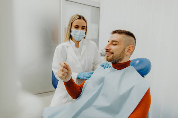 Happy male patient looking in the mirror after dental treatment stock photo