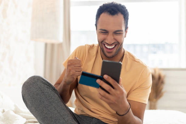 istock Joyful Middle Eastern Man Holding Smartphone And Credit Card Indoor 1466839561