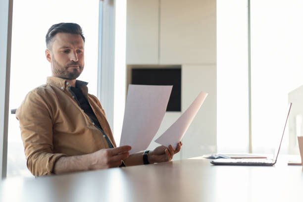 istock Thoughtful Businessman Reading Business Papers Holding Documents Sitting In Office 1466839609
