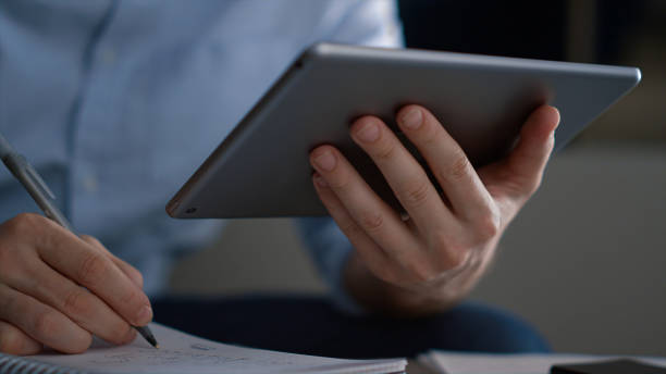 istock Business man researching tablet analyze corporate data writing notes in office. 1466841012