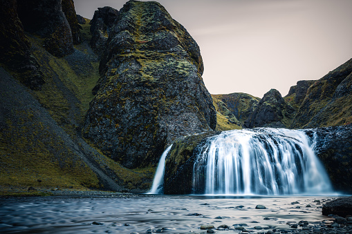 Small waterfall in Ιceland one day with clouds in the sky