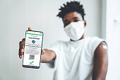 African American teenager shows vaccine passport on mobile phone to validate travel permission by the digital document