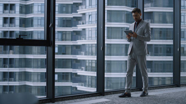istock Focused entrepreneur using tablet researching corporate data in office building. 1466850372
