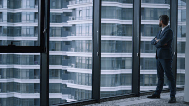 istock Executive man walking office alone. Young businessman standing looking window. 1466850687