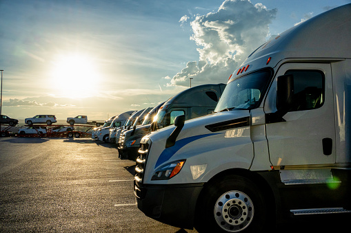 Row of Parked Semi-Trucks at Dusk in a Parking Lot with a Stunning Sunset Cloudscape