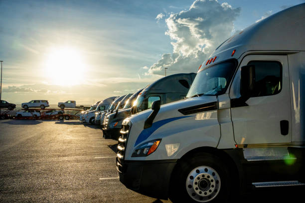 Row of Parked Semi-Trucks at Dusk in a Parking Lot with a Stunning Sunset Cloudscape stock photo