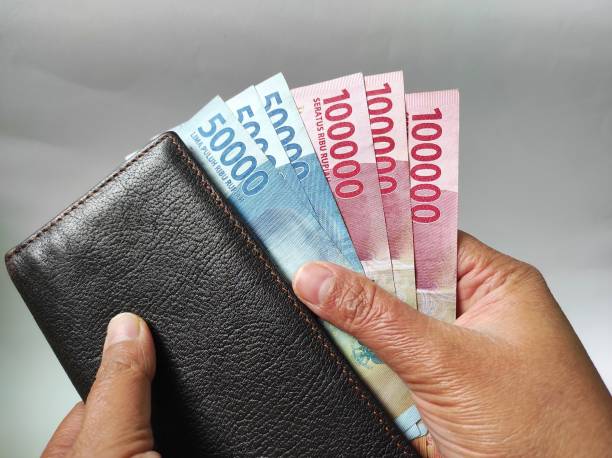 istock Human hands holding 50000 and 100000 rupiah banknotes 1466858573