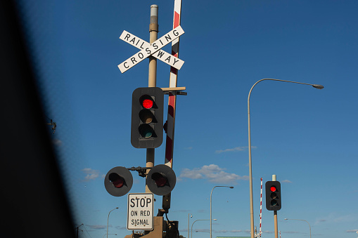 view of a railway crossing sign with red traffic light from inside the car