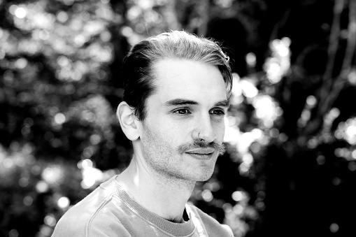 Black and white portrait of 22 years old young man outdoor, background with copy space, full frame horizontal composition