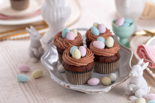 Homemade Easter vanilla cupcakes bird's nest with butter cream, chocolate and candy eggs on a dish. stock photo
