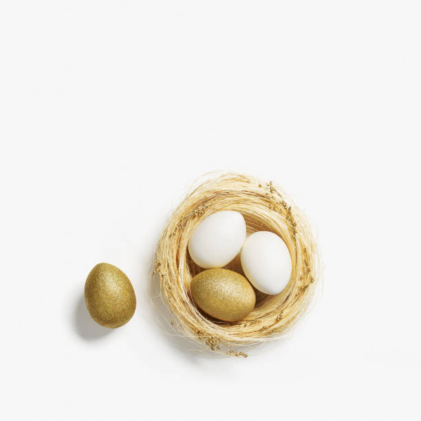 яйца золотистого цвета в гнезде из соломы на белом фоне. стильное золотое яйцо для пасхального весеннего праздника. вид сверху декоративны� - easter nest стоковые фото и изображения