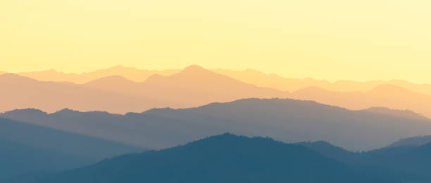 panoramic scene of bright sunlight over the layers of mountain range. - layered mountain peak summer light imagens e fotografias de stock