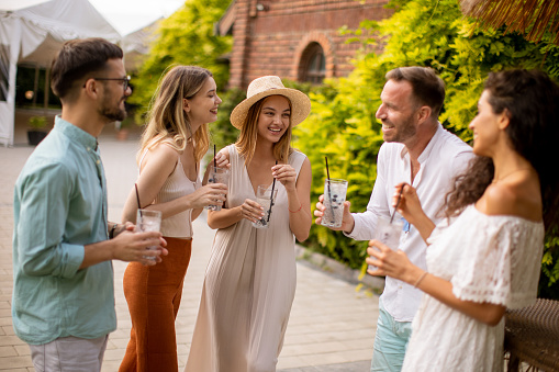 Group of young people gather outdoors to enjoy each other's company and refreshing glasses of lemonade