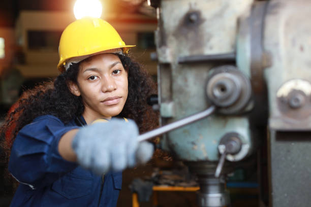 istock Technician engineer or worker woman in protective uniform with safety hardhat maintenance operation or checking lathe metal machine at heavy industry manufacturing factory. Metalworking concept 1466908041