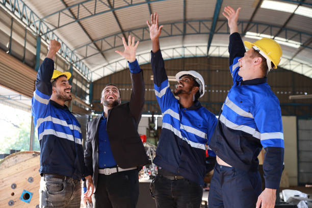 istock Group of technician engineer and businessman in protective uniform with hardhat standing and raising hands celebrate successful together or completed deal commitment at metal lathe factory industry 1466908093