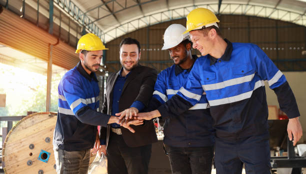 istock Group of technician engineer and businessman in protective uniform with hardhat standing and stacking hands celebrate successful together or completed deal commitment at metal lathe factory industry 1466908104