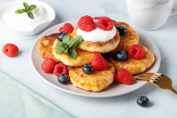 istock Cottage cheese pancakes with raspberries and blueberry on light background, breakfast or lunch 1466912880