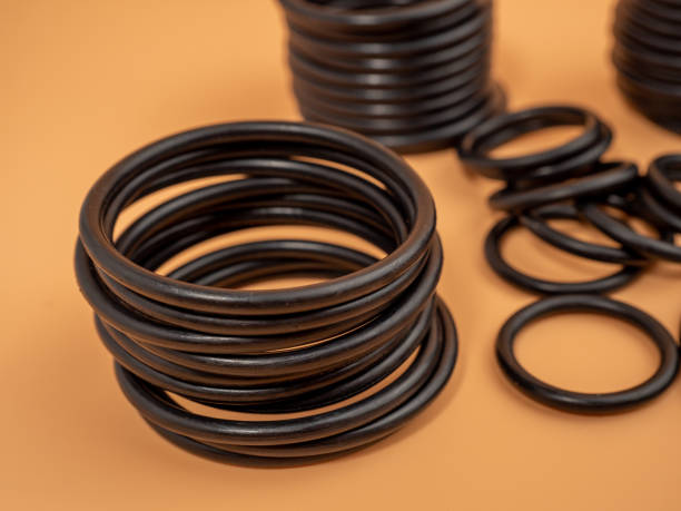 istock Hydraulic and pneumatic o-rings in black in different sizes on an orange background. Rubber gaskets for plumbing. 1466913294