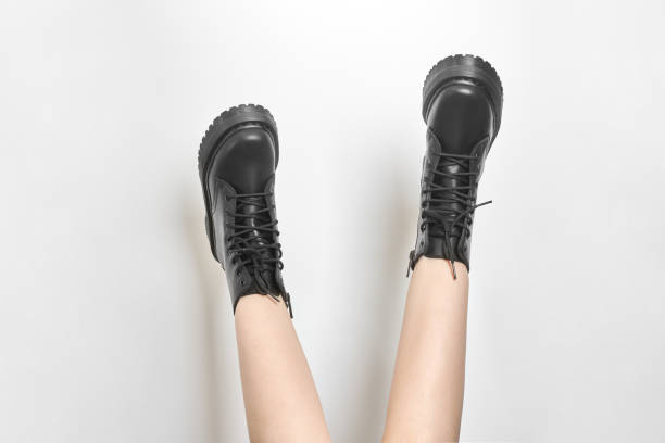 istock Woman legs in black combat boots on high heel platform with lug soles upside down, white background 1466914701
