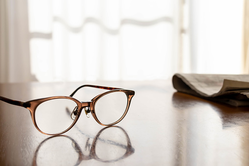 Glasses and newspapers placed in the living room where the sun shines