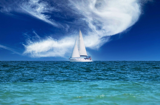 Sailboat on the waves of the sea. Fabulous sky in the background.