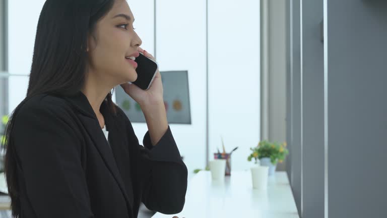 Businesswoman relaxing break in company office room and answering calls on smartphone.