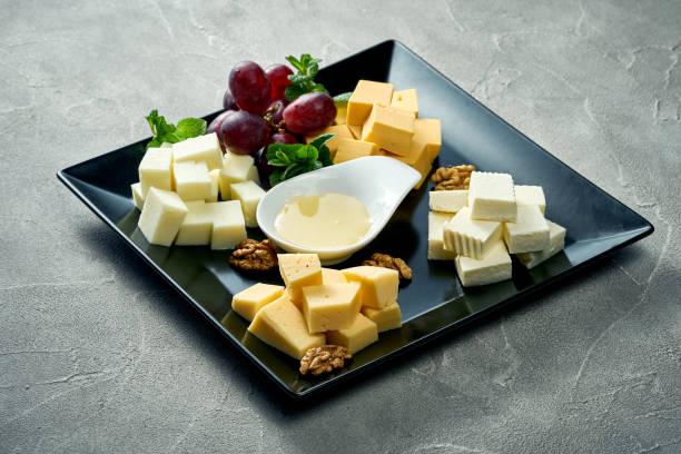 Cheese plate with different types. Concrete background. Assorted cheeses for an appetizer in a black plate stock photo