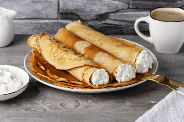 Thin pancakes with cottage cheese with sour cream and coffee. Healthy traditional breakfast concept Thin pancakes with cottage cheese with sour cream and coffee. Healthy traditional breakfast concept. 1354 stock pictures, royalty-free photos & images