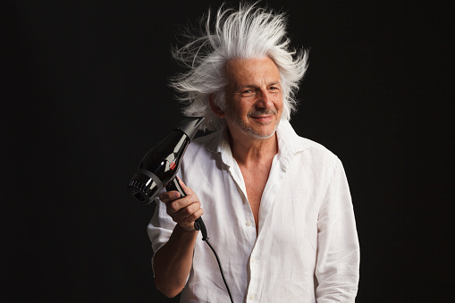 Beauty portrait Romantic  senior man, unshaved, blow-dry,  with wind white long hair. black backgrounds. Facial expressions.