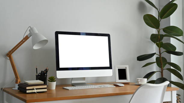 istock Modern workplace with blank computer screen, lamp and supplies on wooden desk. Empty screen for your advertising design 1466933791