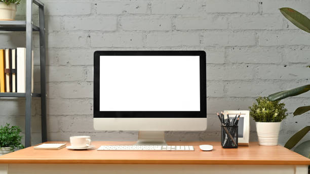istock Comfortable workplace with computer and supplies against brick wall. Blank screen for graphic display montage. 1466933794