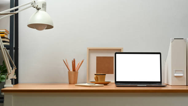 istock Bright home office interior with laptop computer, picture frame, potted plant and picture frame on wooden desk. 1466933839