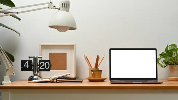 istock Bright home office interior with laptop computer, picture frame, potted plant and picture frame on wooden desk. 1466933890
