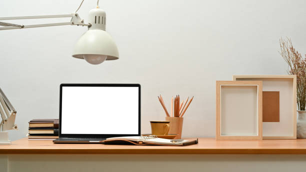istock Comfortable home office interior with laptop computer, lamp, photo frame and stationery on wooden desk. 1466933896