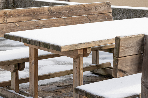 Snowy winter urban outdoor furniture, wooden table and benches
