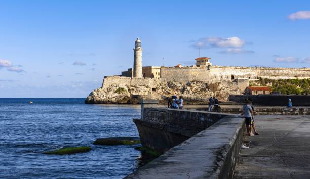 Morro Castle in Havana Havana, Cuba, November 20, 2017: View of the Castillo De Los Tres Reyes Del Morro (Morro Castle), seen from toe Malecón promenade. It is a fortress guarding the entrance to Havana Bay. city street street corner tree stock pictures, royalty-free photos & images