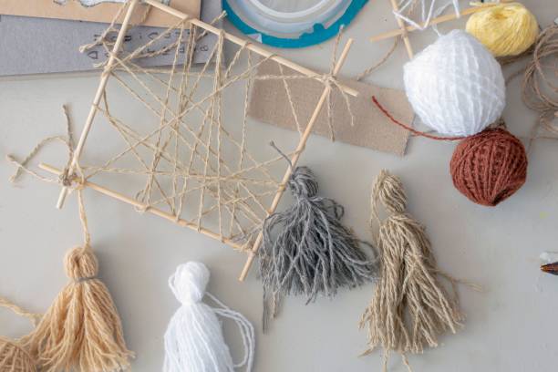 istock Work of designer - multi-colored tassels made of woolen thread, wooden frame lie on table. 1466938891