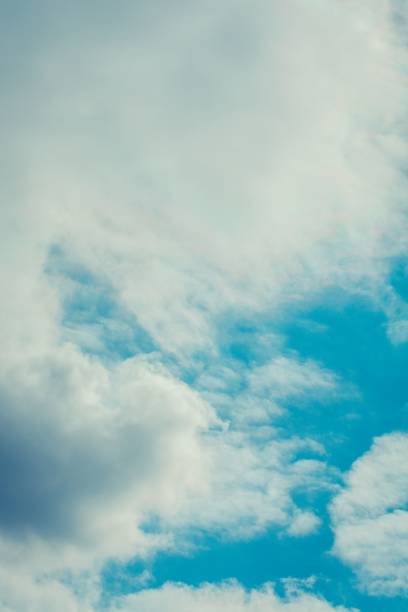 A vertical shot of white dense fluffy clouds in the blue sky