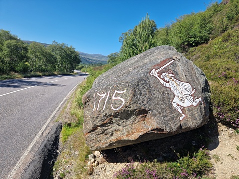 A large rock on the side of a road, providing a beautiful backdrop for travelers