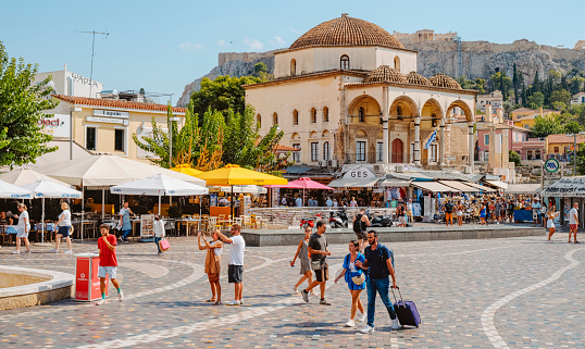 Athens, Greece - August 29, 2022: Some tourist walkin by Monastiraki Square, in Athens, Greece, with the Tzistarakis Mosque in the background